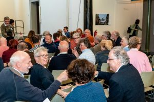 Begroeting met op de achtergrond foto's van de tentoonstelling 'Zie mij!'.
